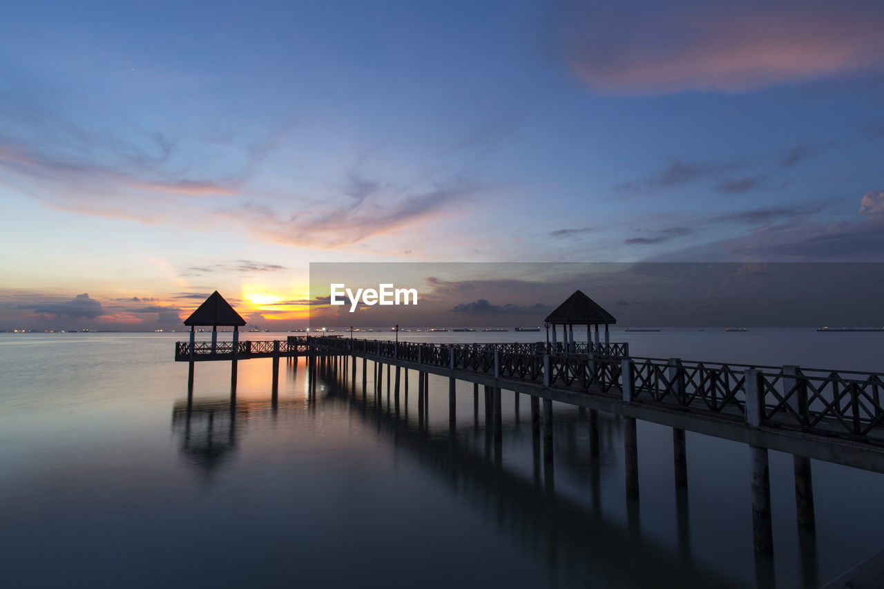 Silhouette pier over sea against sky during sunset