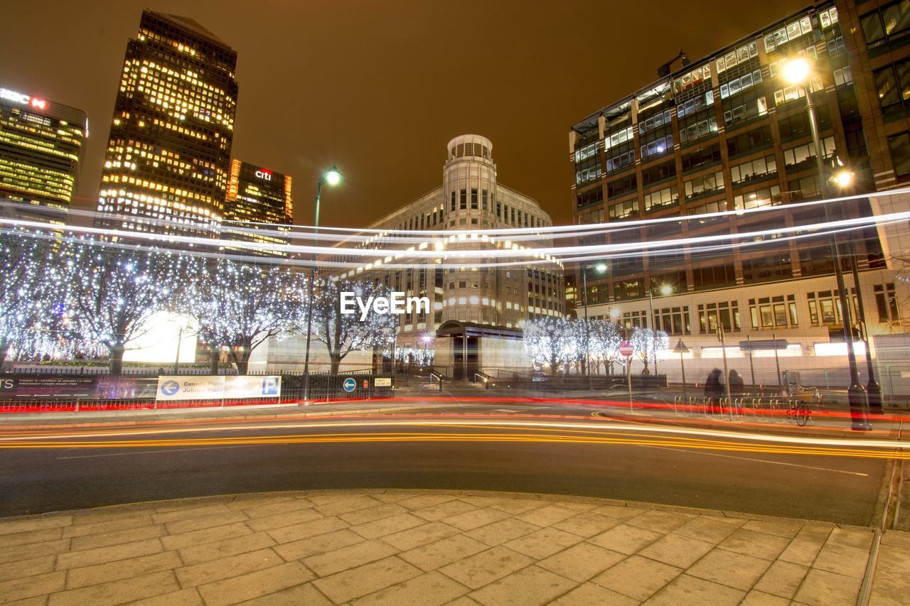 Light trails on road against buildings at night