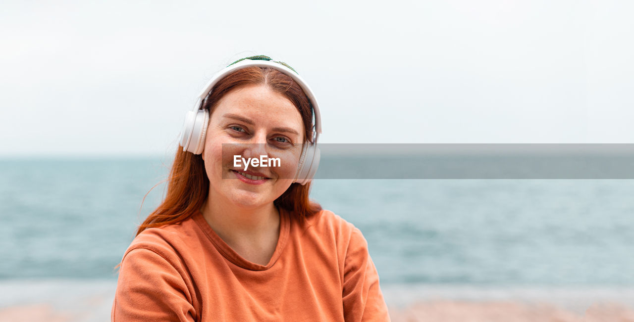 Portrait of woman wearing headphones at beach