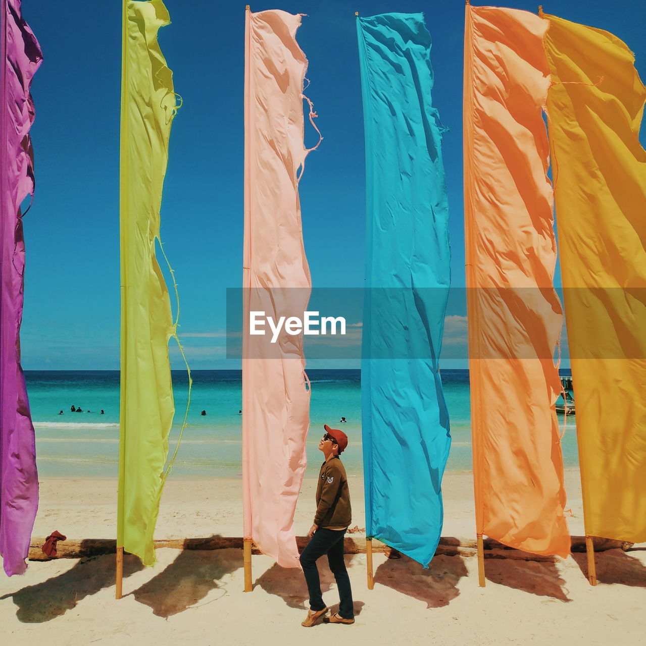 Man walking by flags at beach