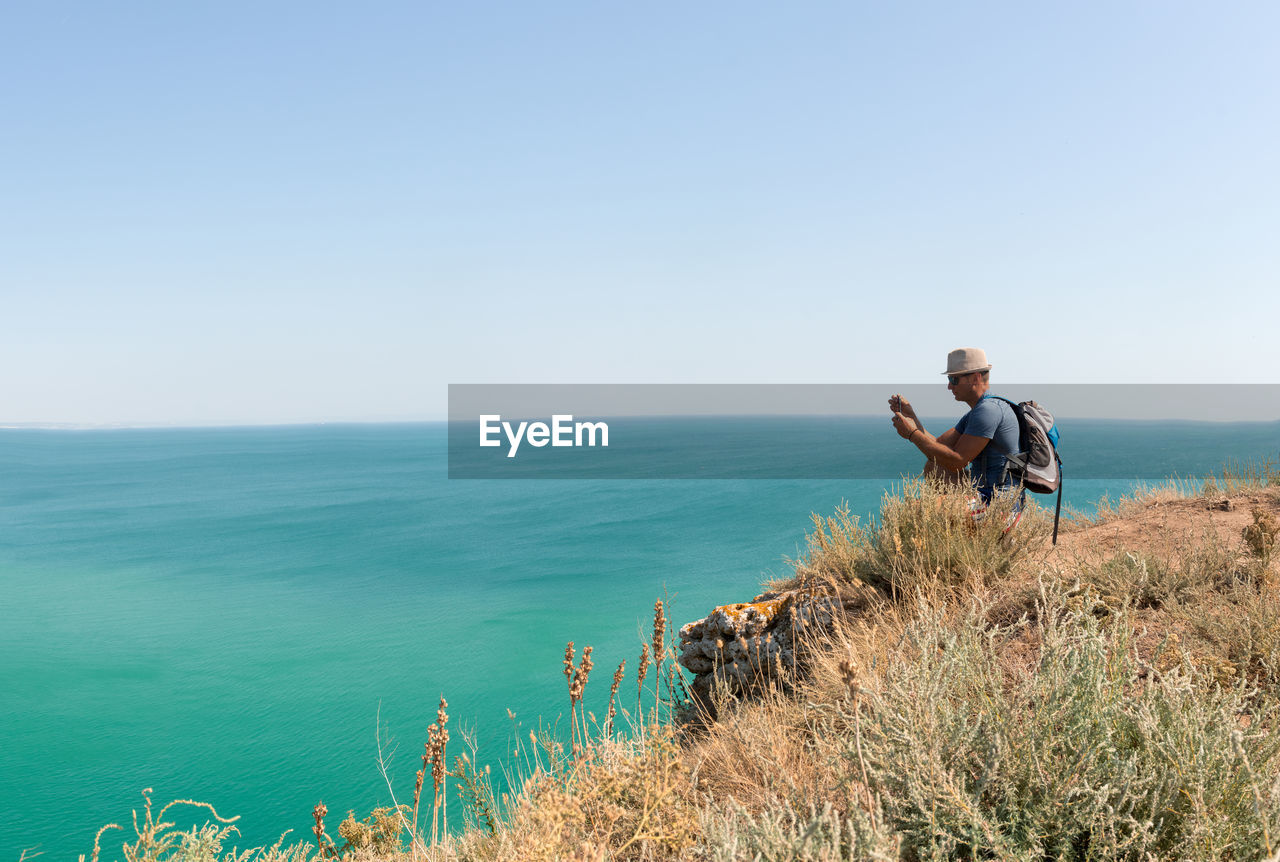 View over turquoise sea in bulgaria with adult man photographing