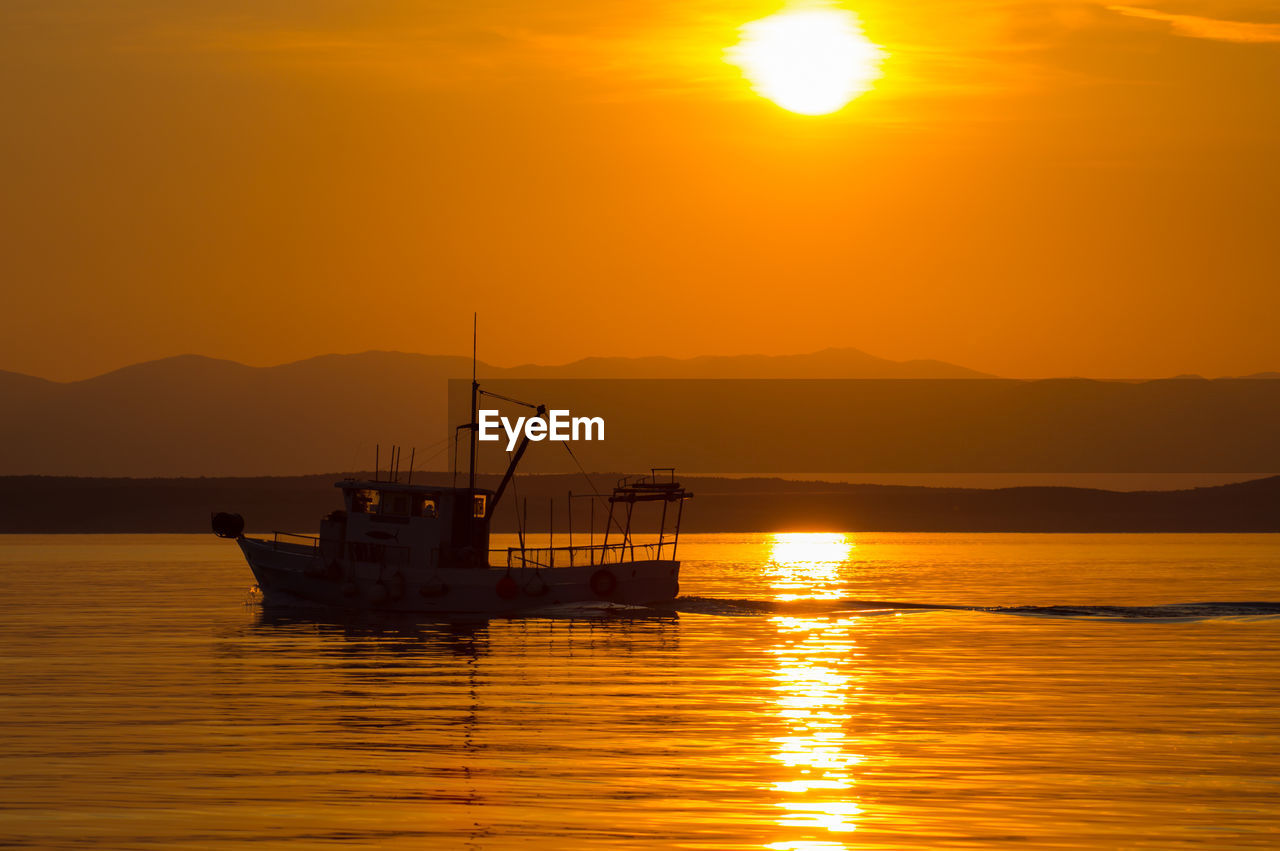 Trawler in the glow of the setting sun. a silhouette off croatia's coast.