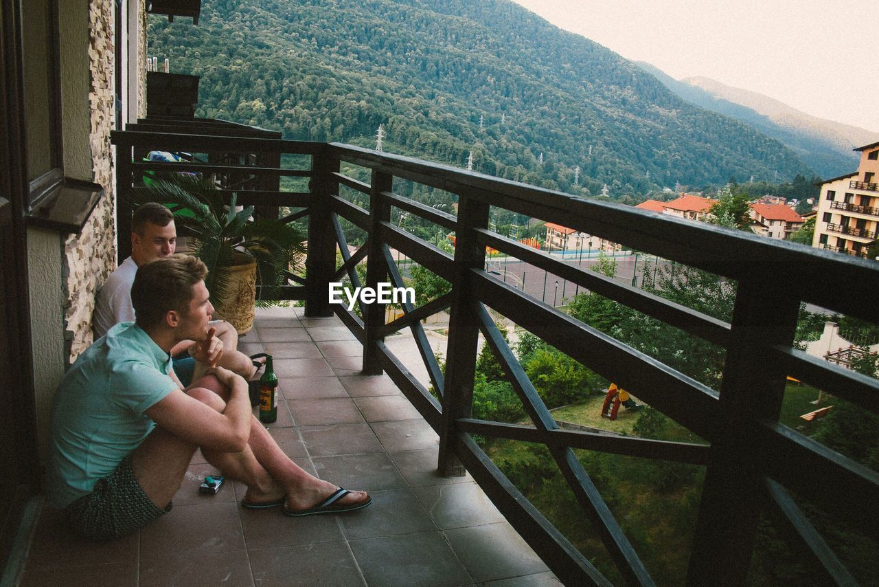 PEOPLE SITTING ON RAILING