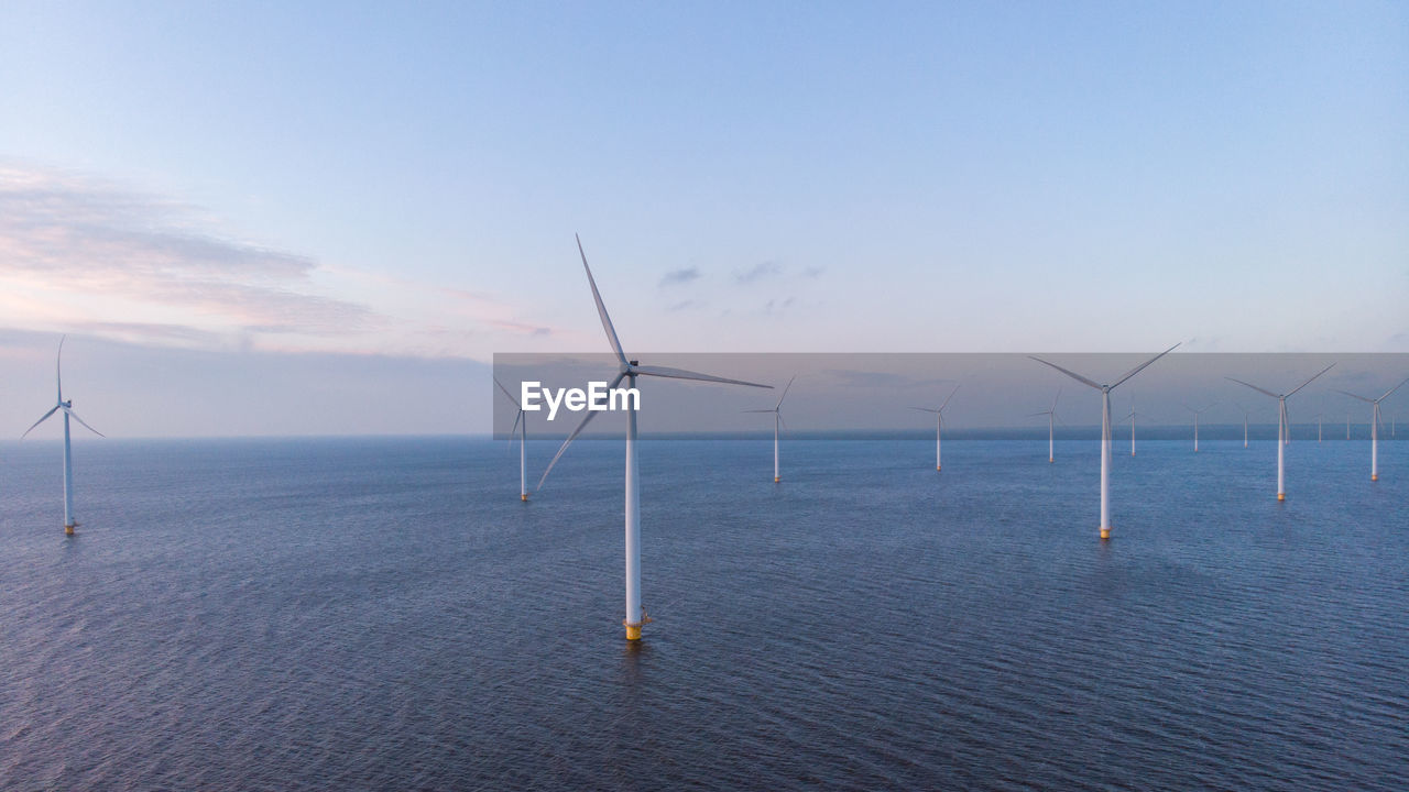 Wind turbines in sea against sky during sunset, windmill turbines in the netherlands 