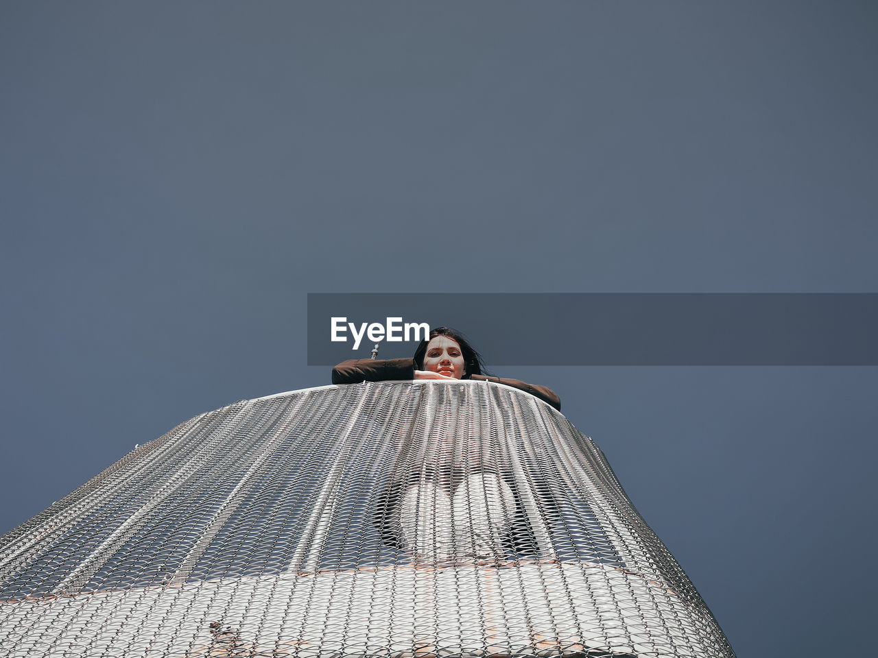 Low angle portrait of woman standing against clear sky