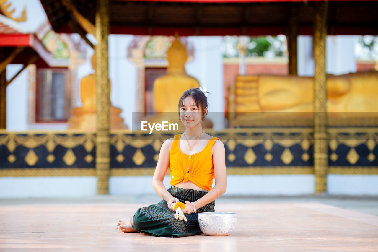 portrait of young woman sitting on street