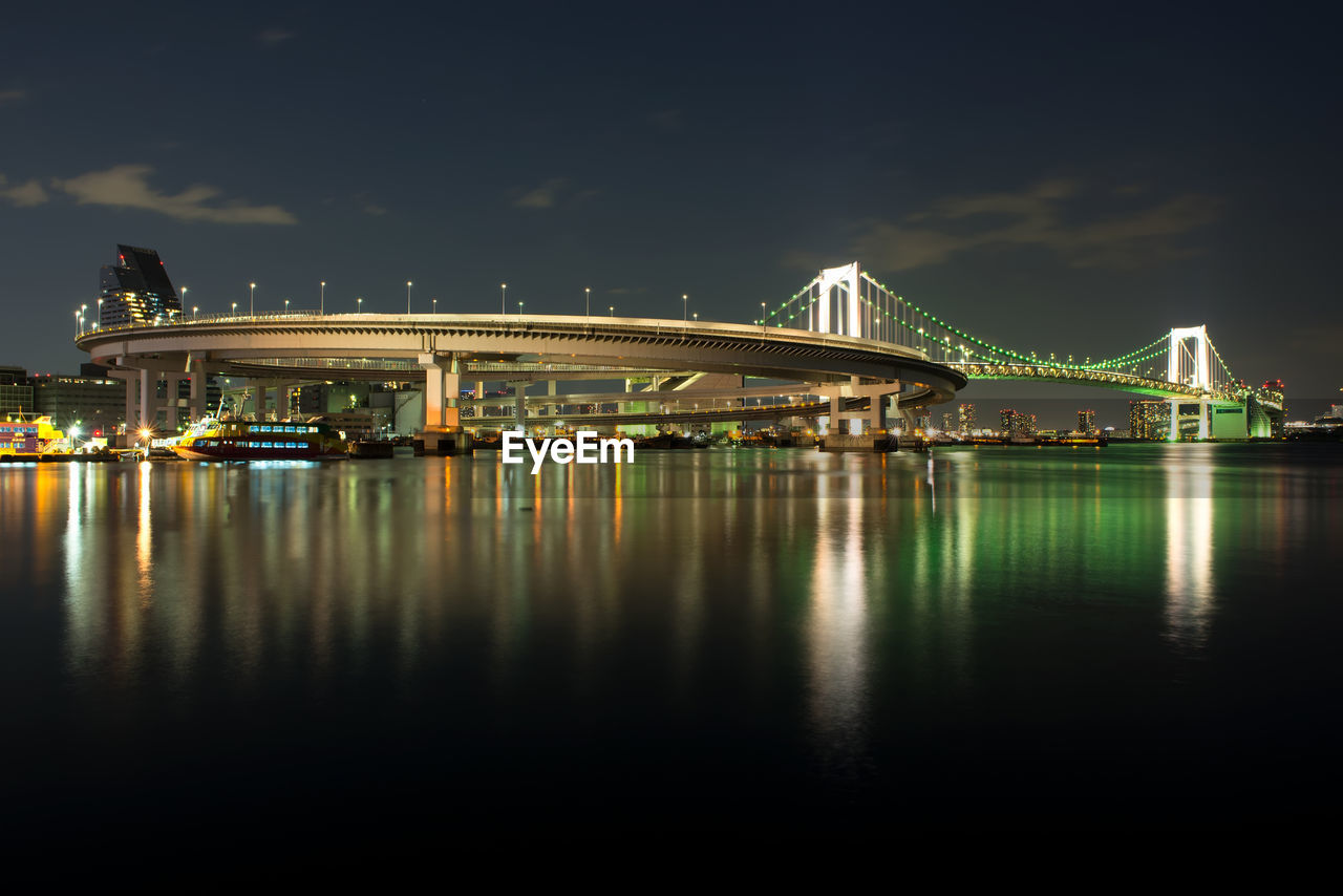 Illuminated bridge over river at night