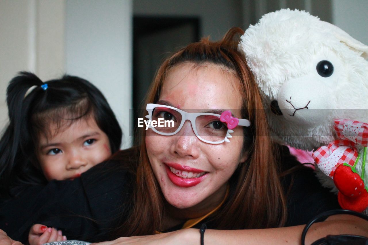 Portrait of smiling woman wearing eyeglasses by daughter at home