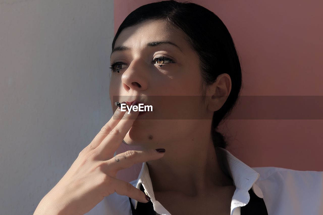 Close-up portrait of a beautiful young woman with cigarette