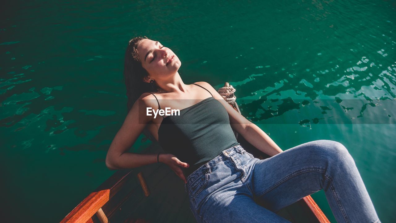 Young woman sleeping in boat on lake