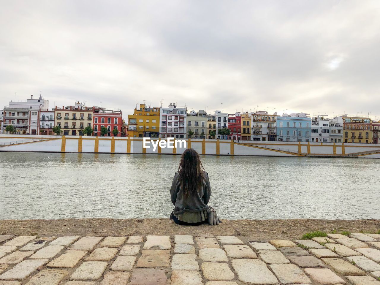 Rear view of woman looking at river against buildings in city