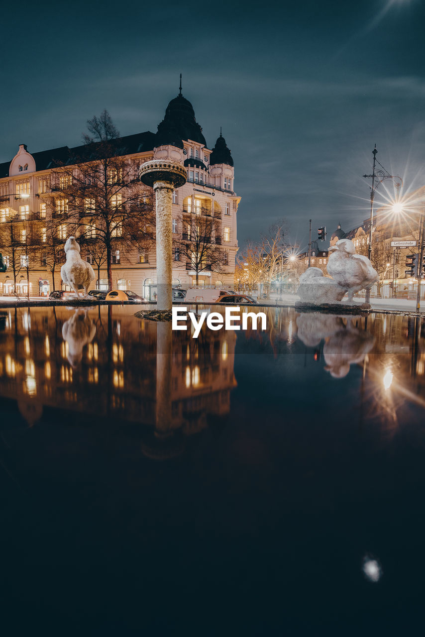 Reflection of buildings in lake at night