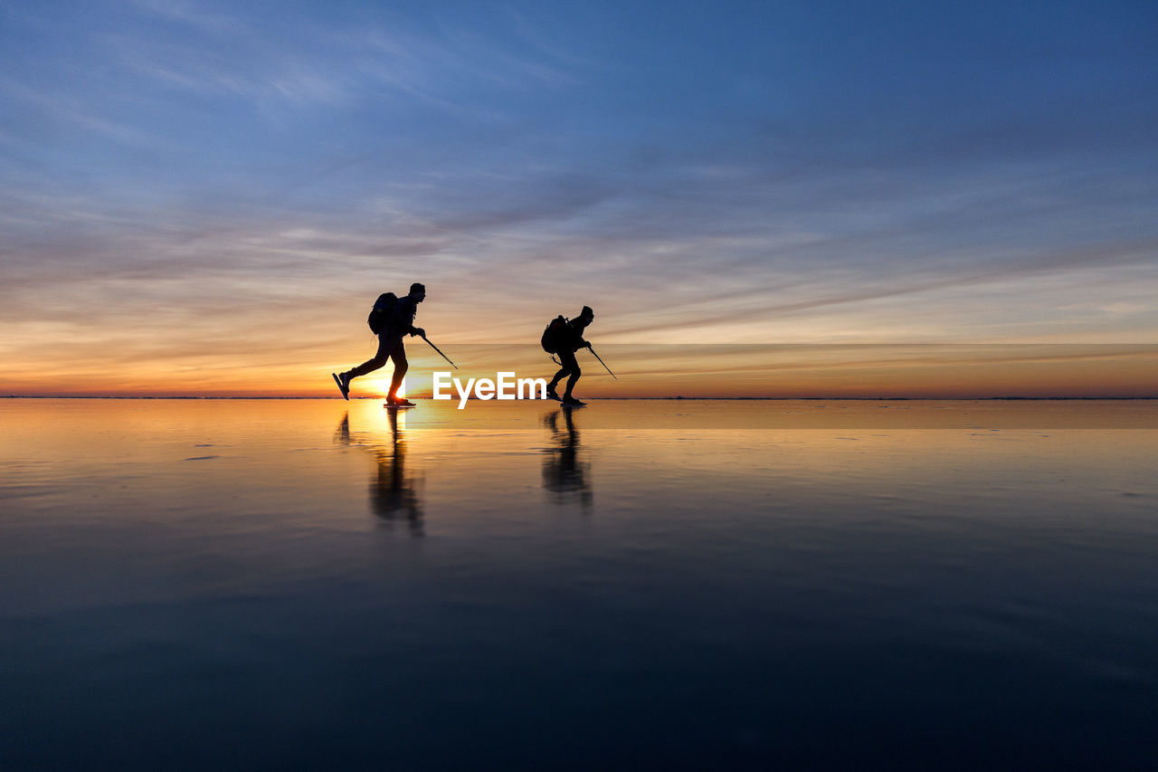 People long-distance skating at sunset, vanern, sweden