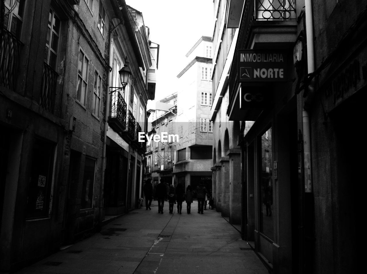 PEOPLE WALKING ON FOOTPATH AMIDST BUILDINGS