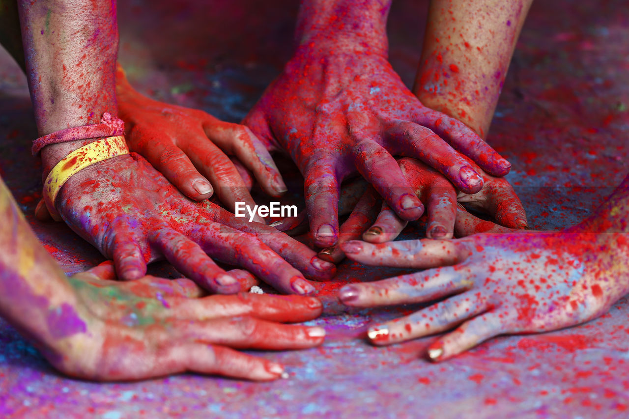 Cropped friends hands covered with powder paints during holi