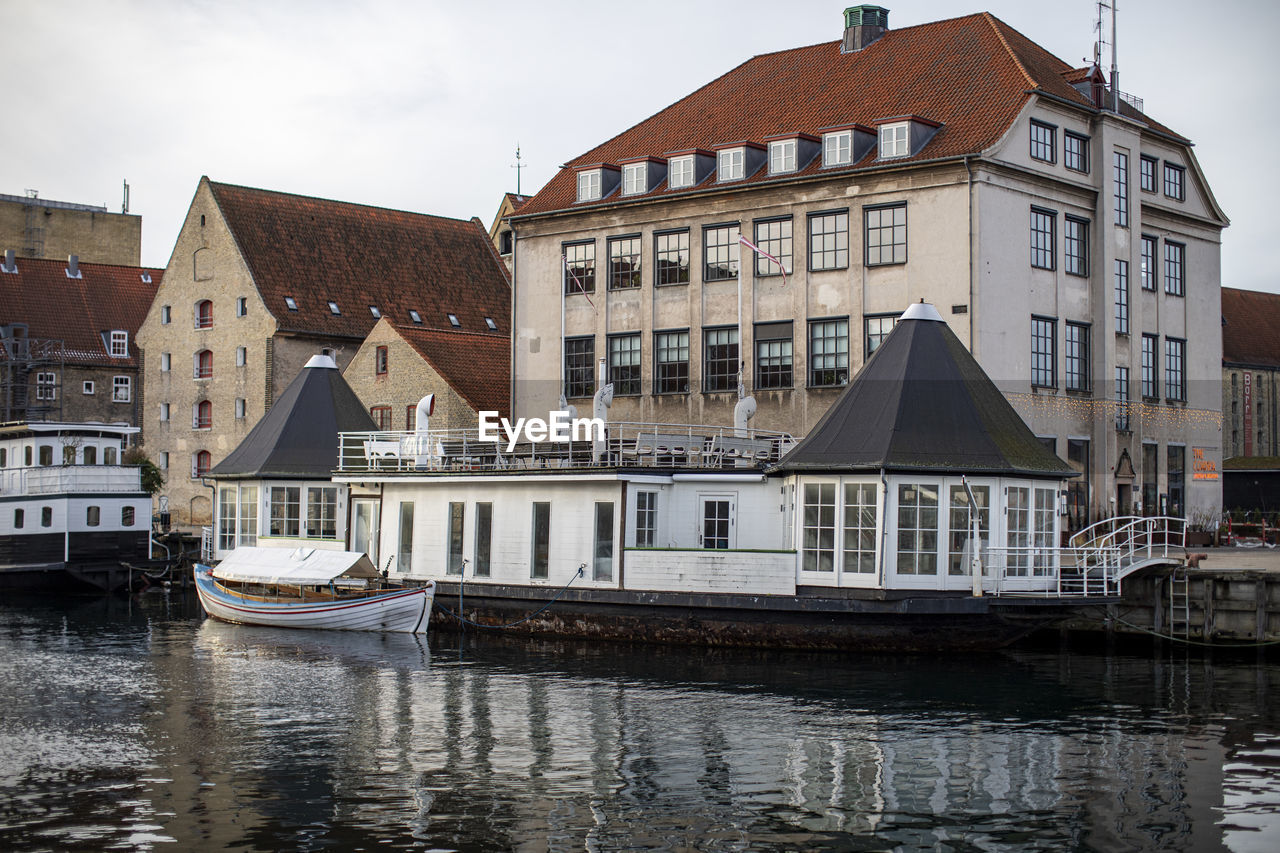 Sailboats moored on canal by buildings in city