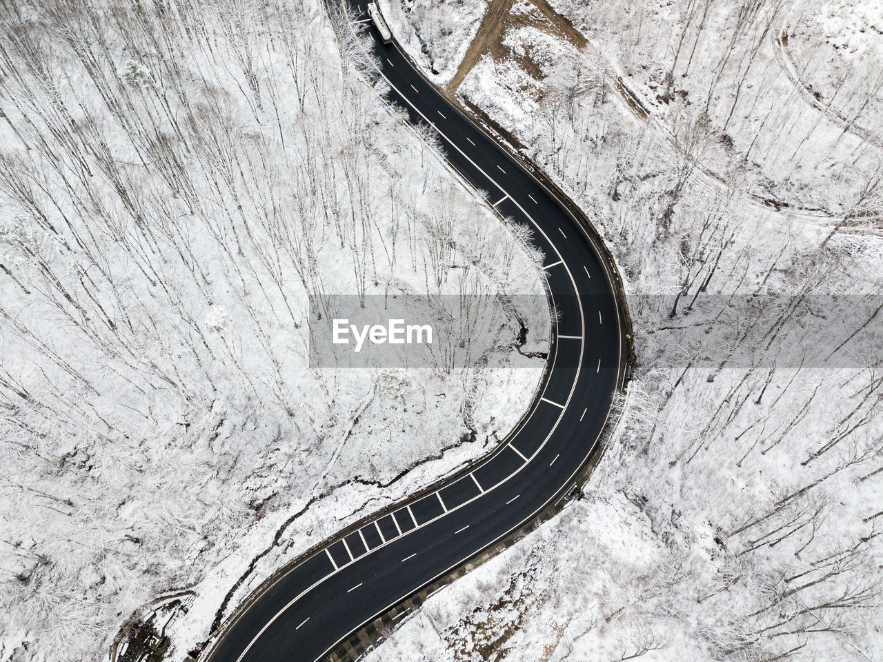 Winding road through the forest, from high mountain pass, in winter time