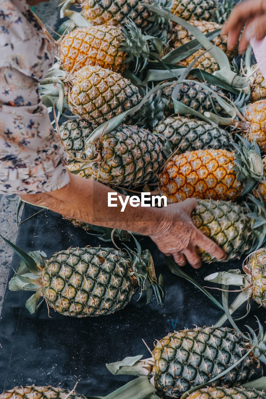 High angle view of senior woman buying pineapple at market stall