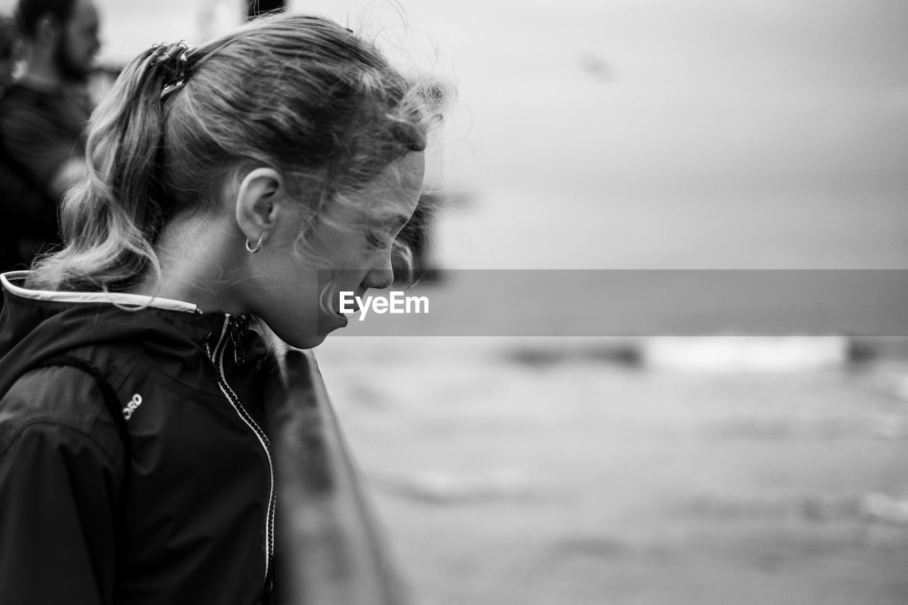 Side view of young woman against sea