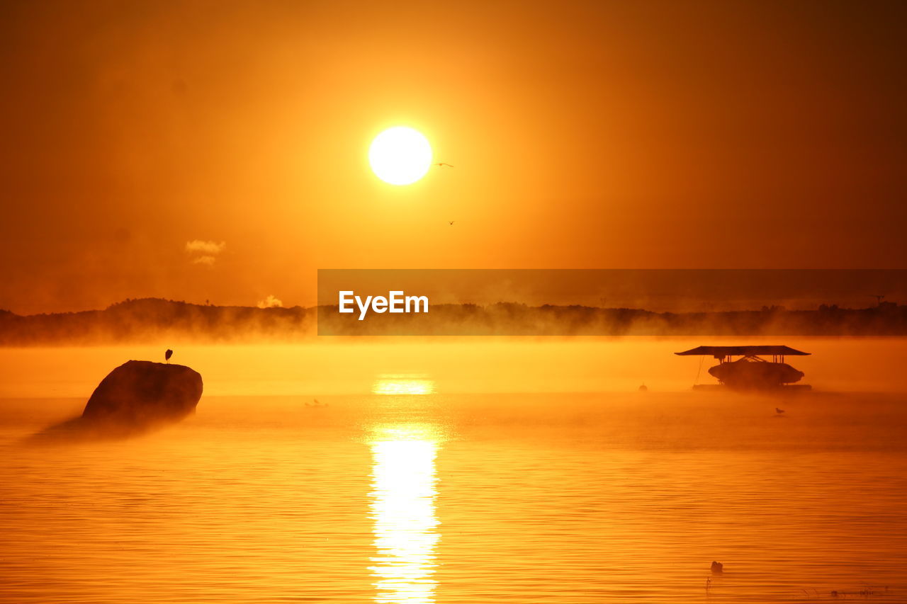 Scenic view of sea against orange sky