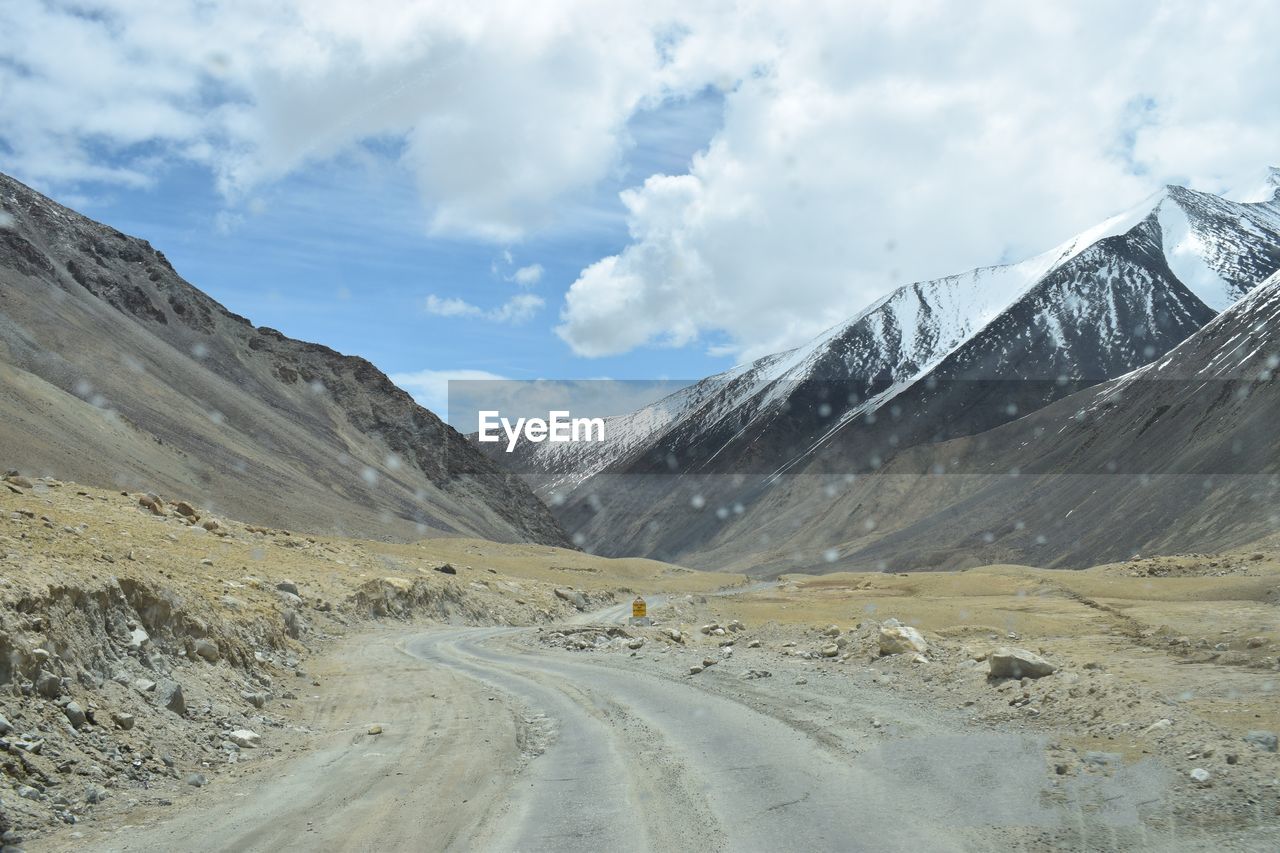 Road by mountains against sky