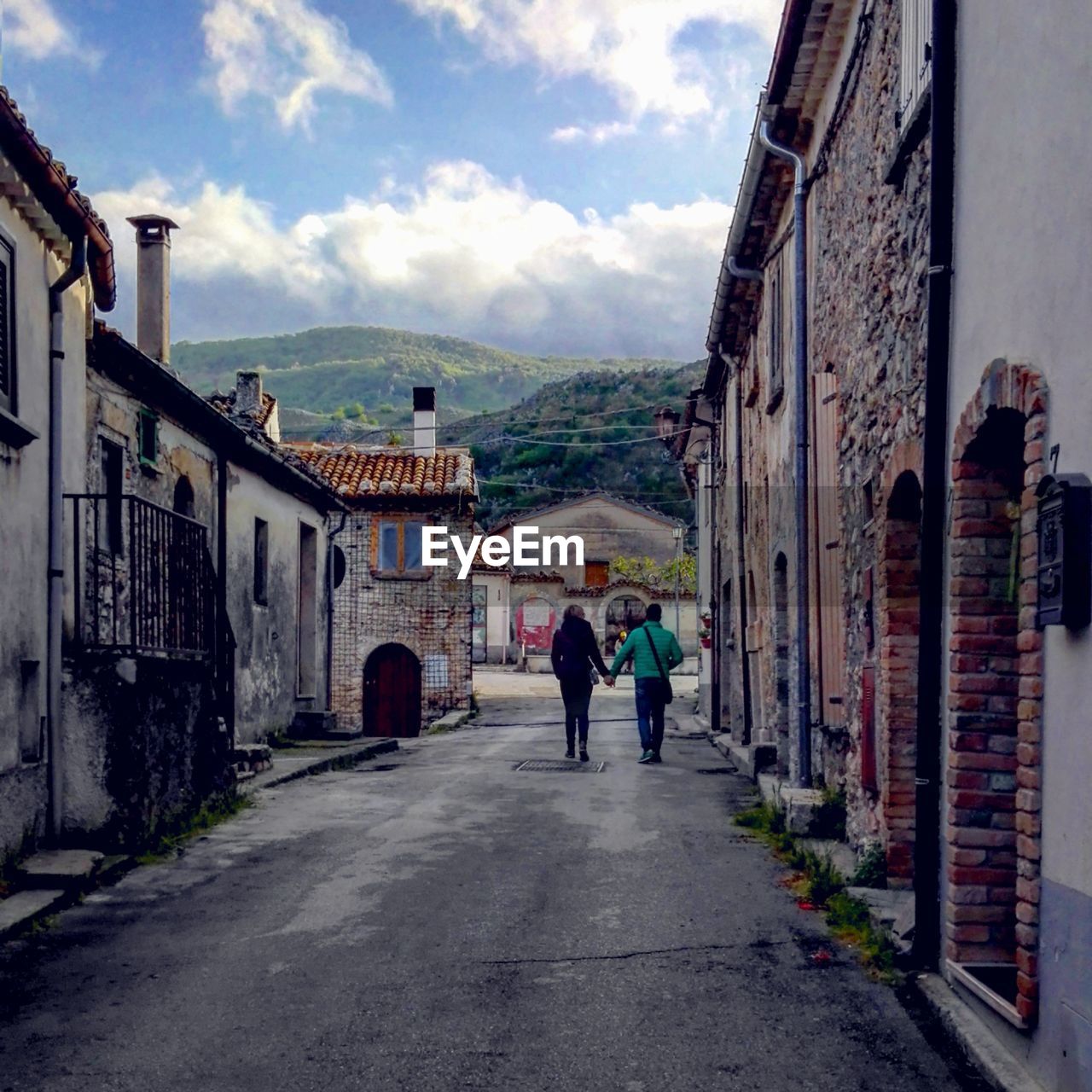 PEOPLE WALKING ON ROAD AMIDST BUILDINGS