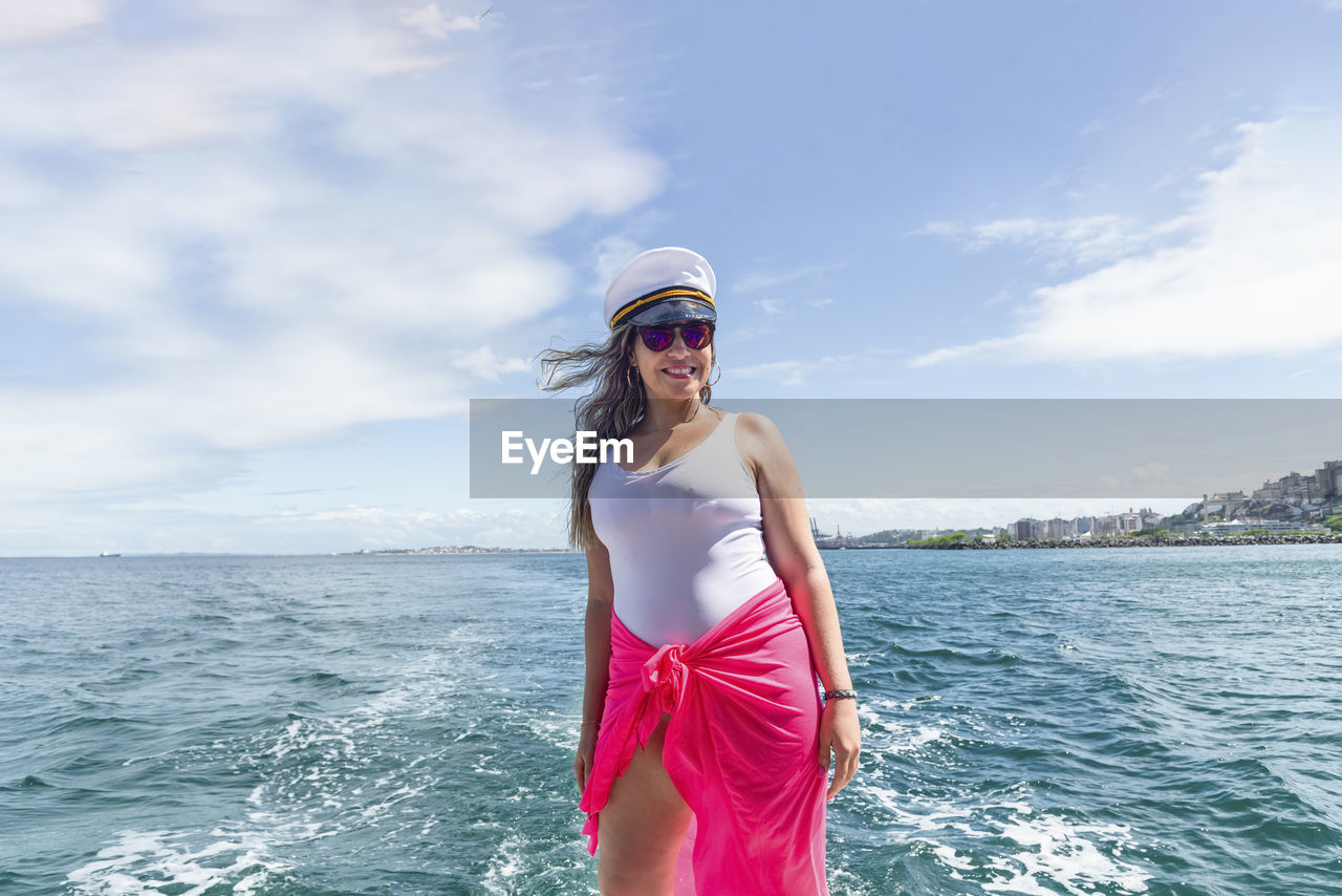 A woman on top of a boat against the sea in the background. 