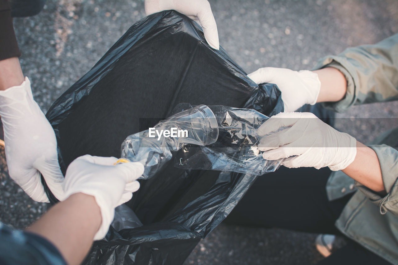 High angle view cropped hands collecting waste on road