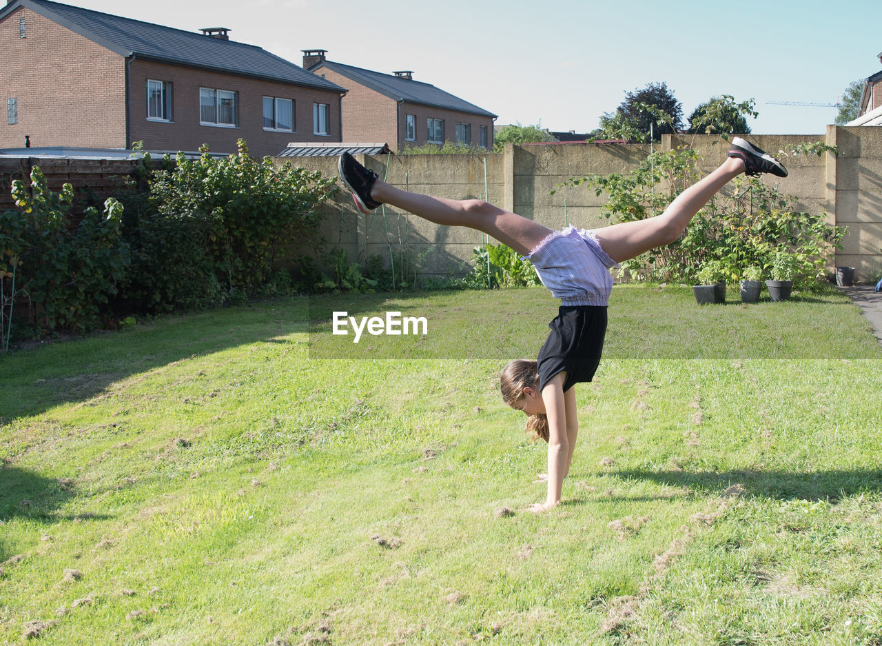 Teenage girl doing acrobatic exercises on a green lawn, sport, generation z,