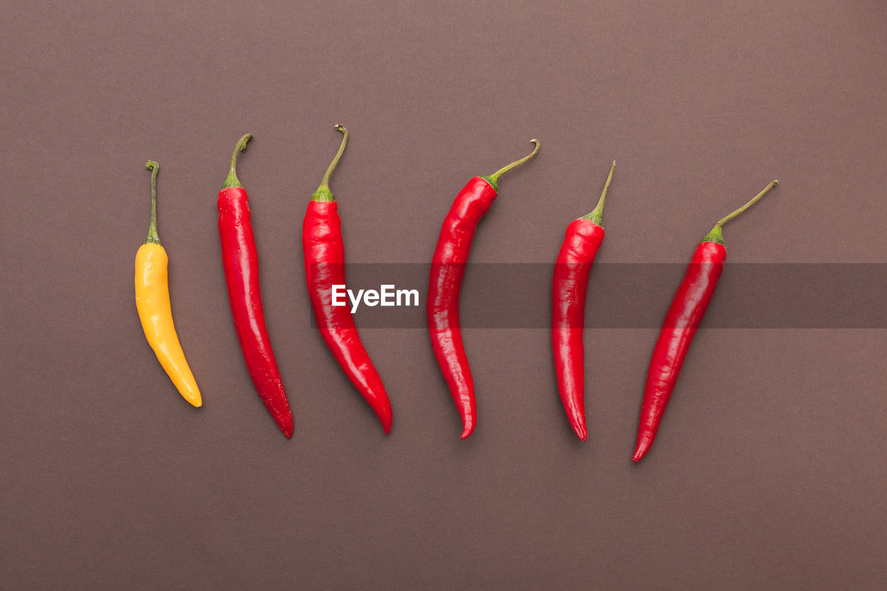 Red and yellow chili peppers isolated on brown background