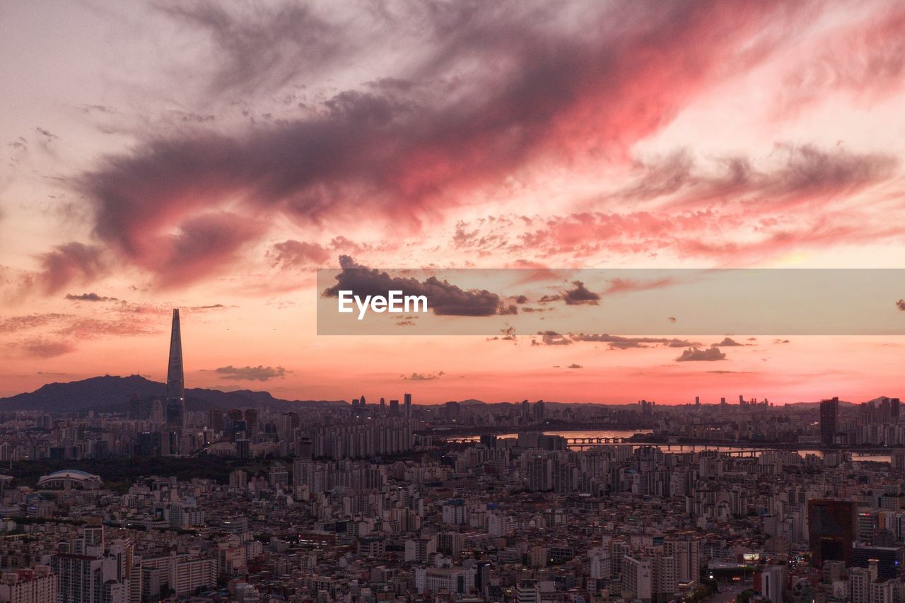 High angle view of city against cloudy sky during sunset