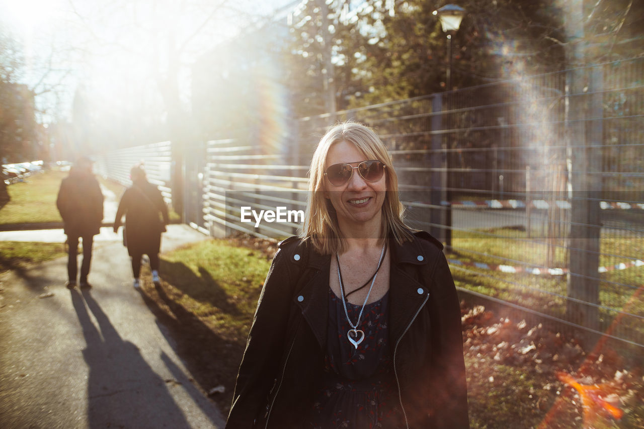 Portrait of smiling woman wearing sunglasses standing in park