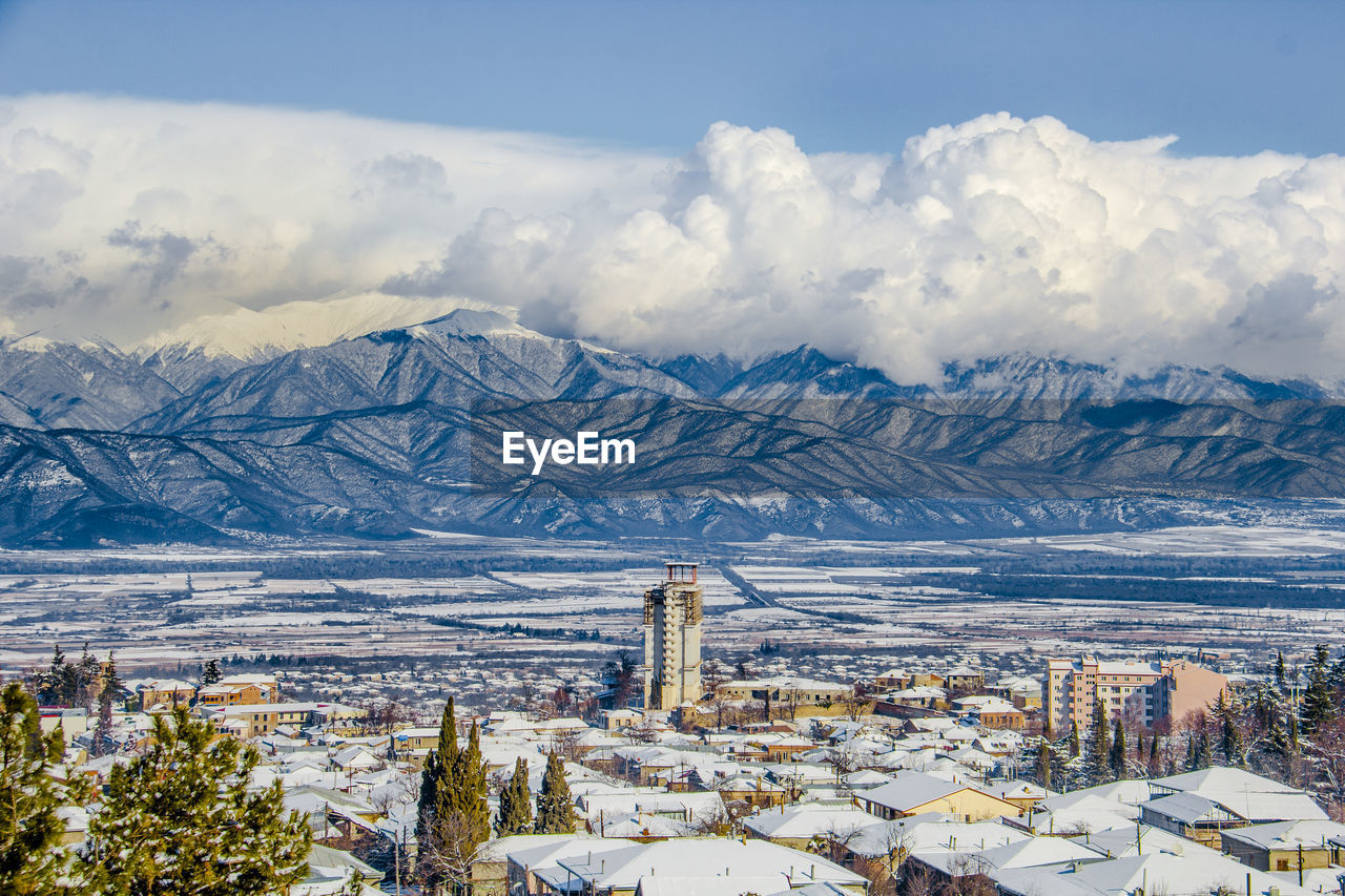 Aerial view of cityscape and mountains against sky during winter