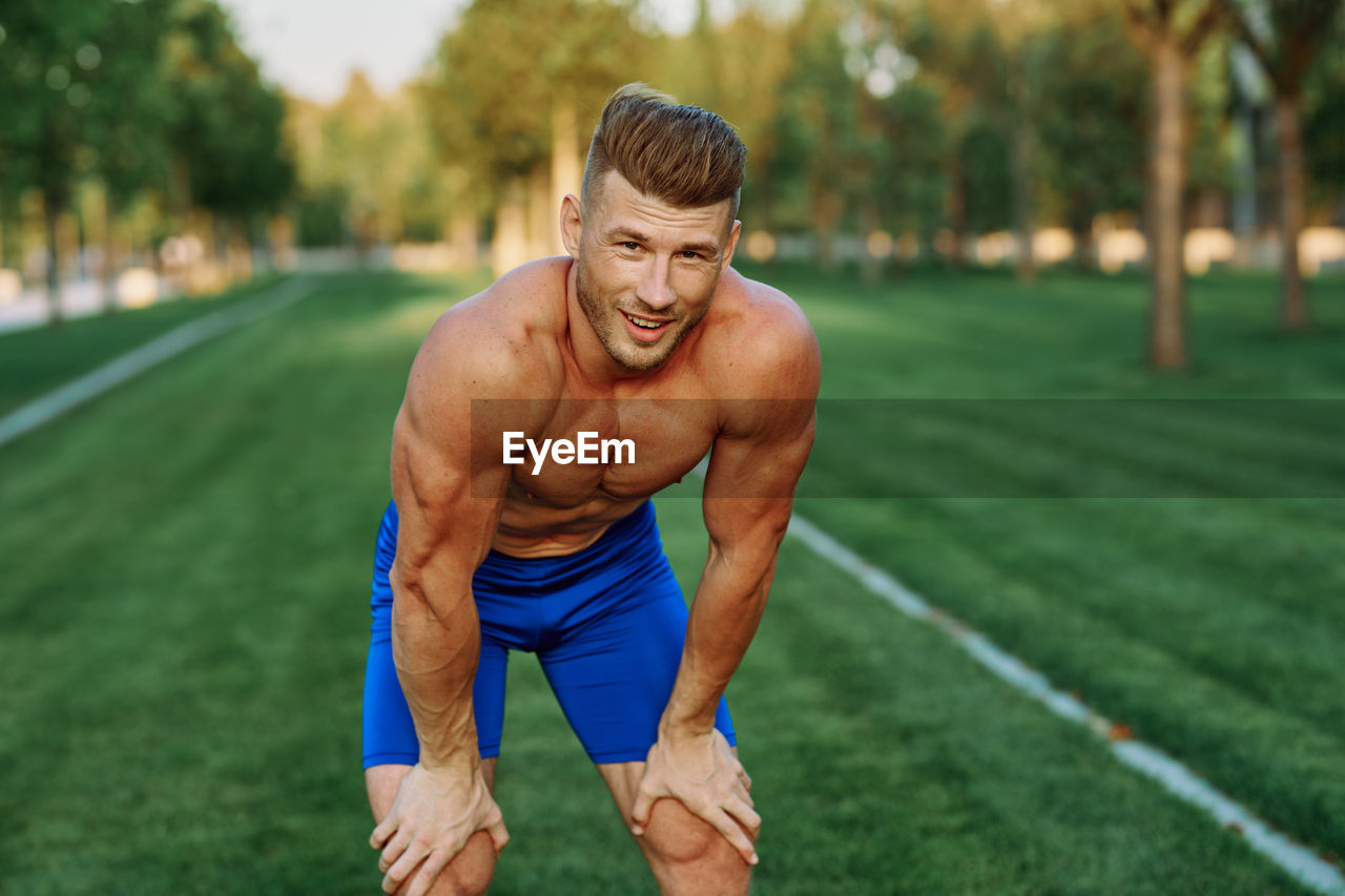 portrait of shirtless young man exercising in park