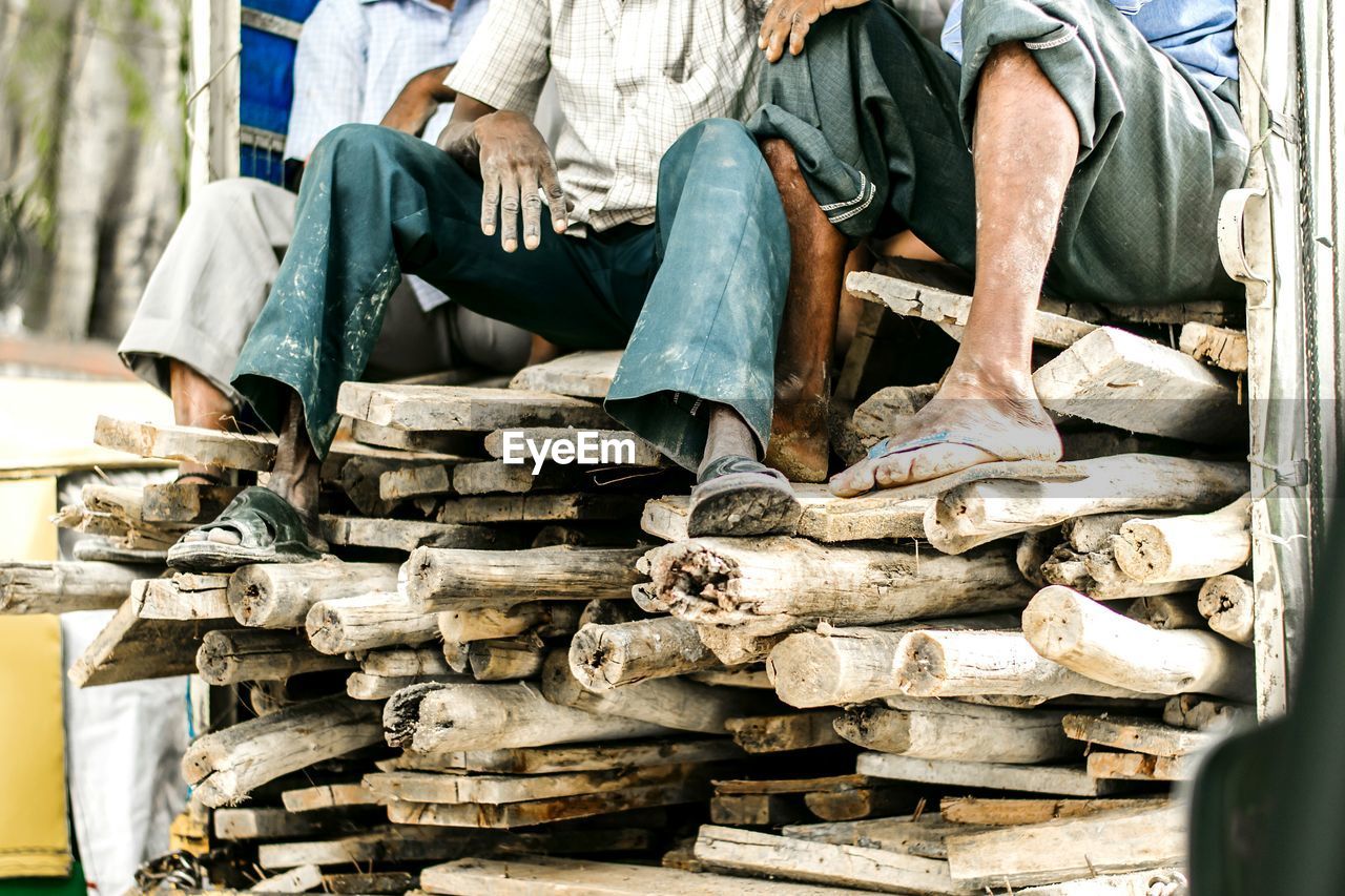 Low section of men on stack of logs