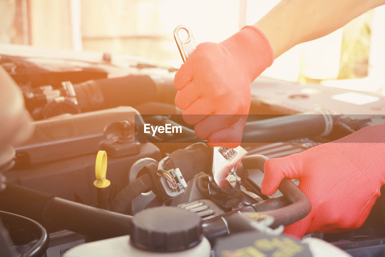 Cropped hands of mechanic repairing car engine