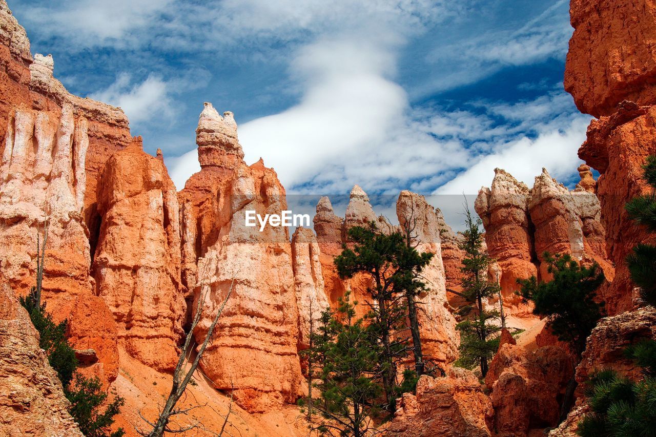 Panoramic view of rocks and trees against cloudy sky