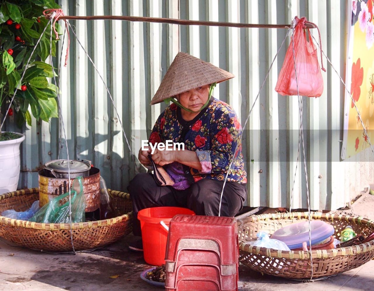 REAR VIEW OF WOMAN SITTING ON WALL