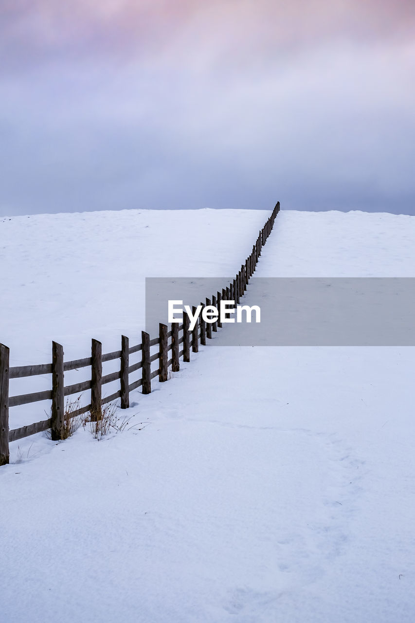 WOODEN POSTS ON SNOW COVERED LAND