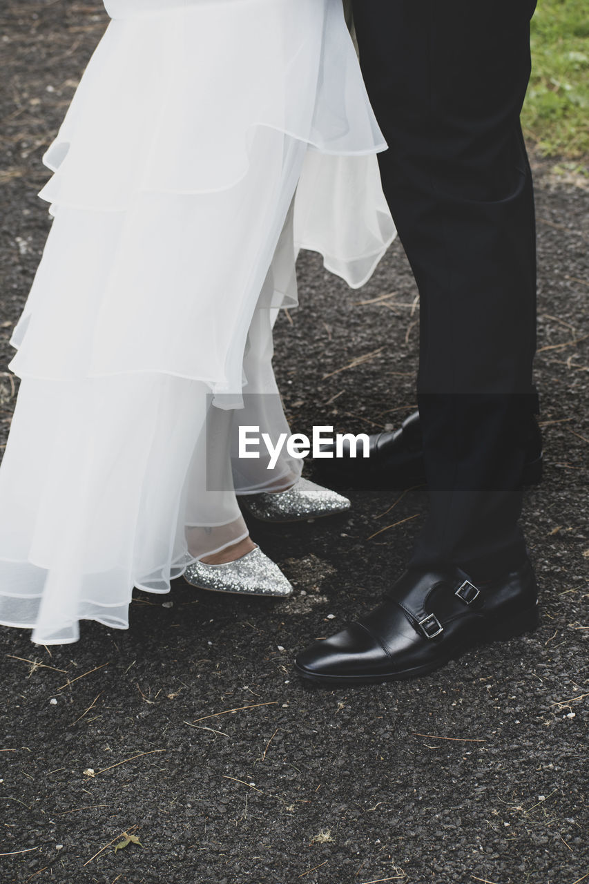 Low section of couple standing on dirt road