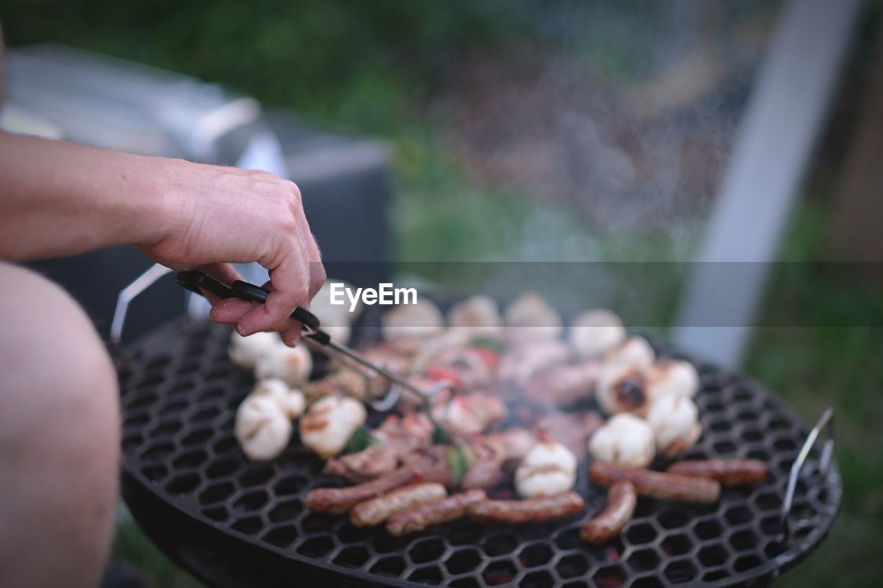 Midsection of man preparing food on barbecue grill