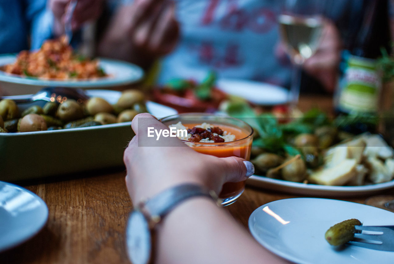 Cropped image of hand holding food in bowl on table