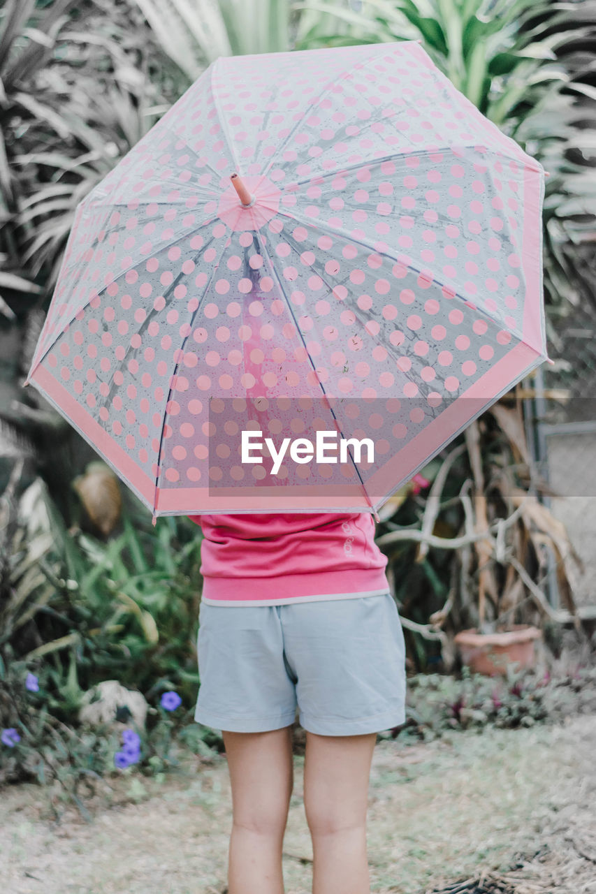 REAR VIEW OF WOMAN WITH PINK UMBRELLA STANDING IN RAIN