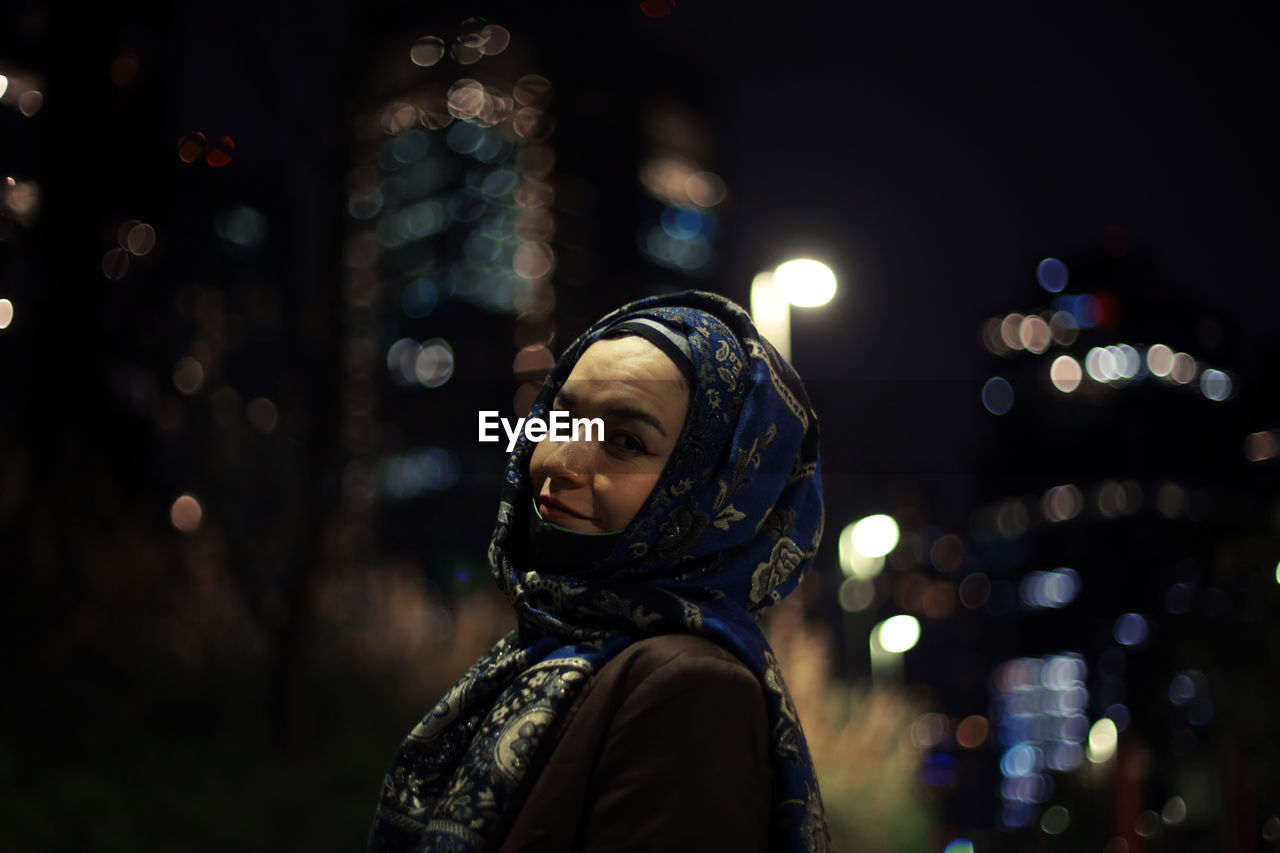 Portrait of woman wearing hijab in city at night