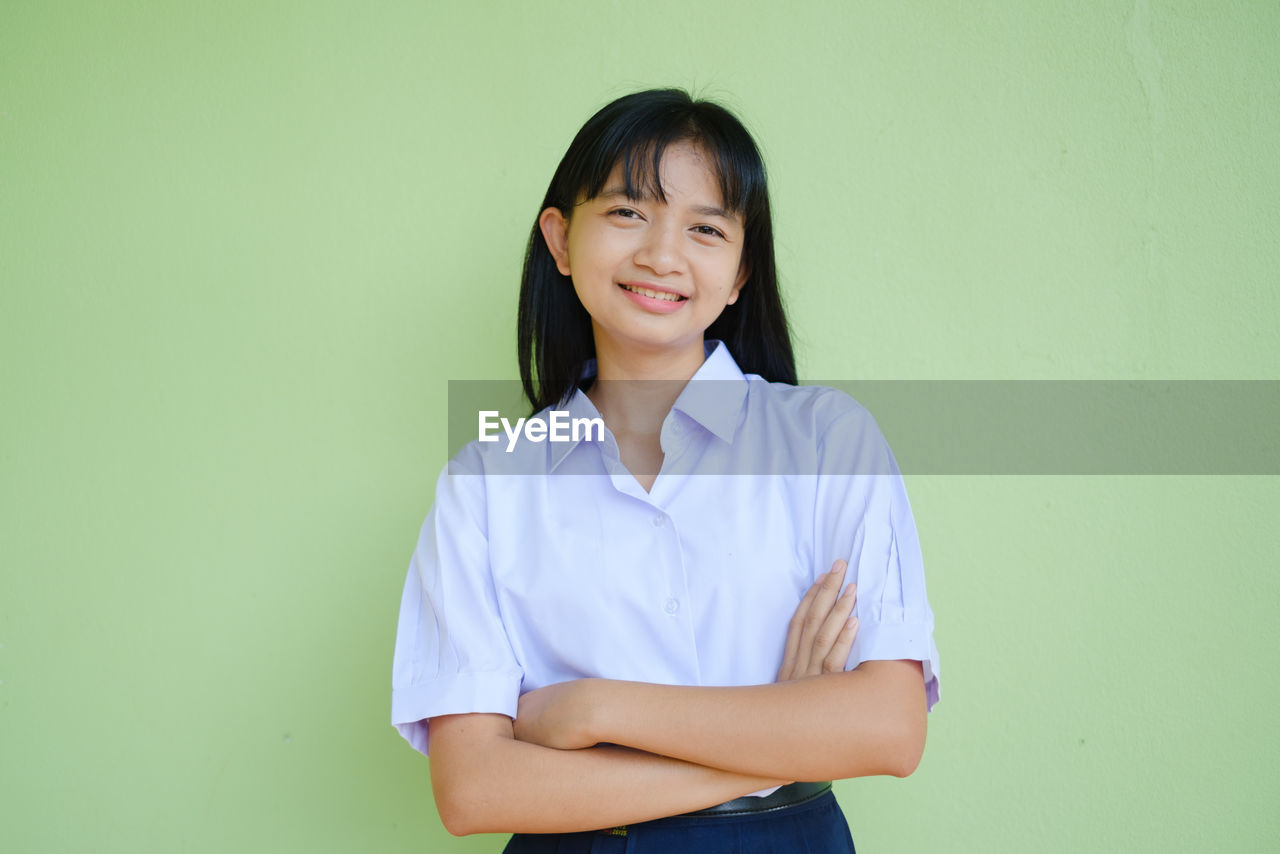 PORTRAIT OF A SMILING YOUNG WOMAN AGAINST BLUE BACKGROUND