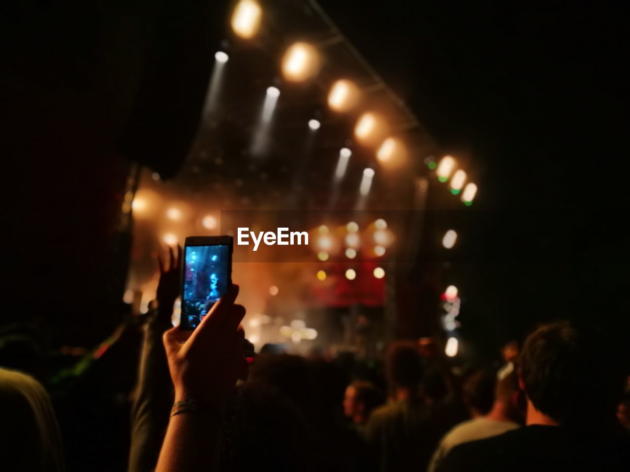 Cropped hand photographing with smart phone during music concert