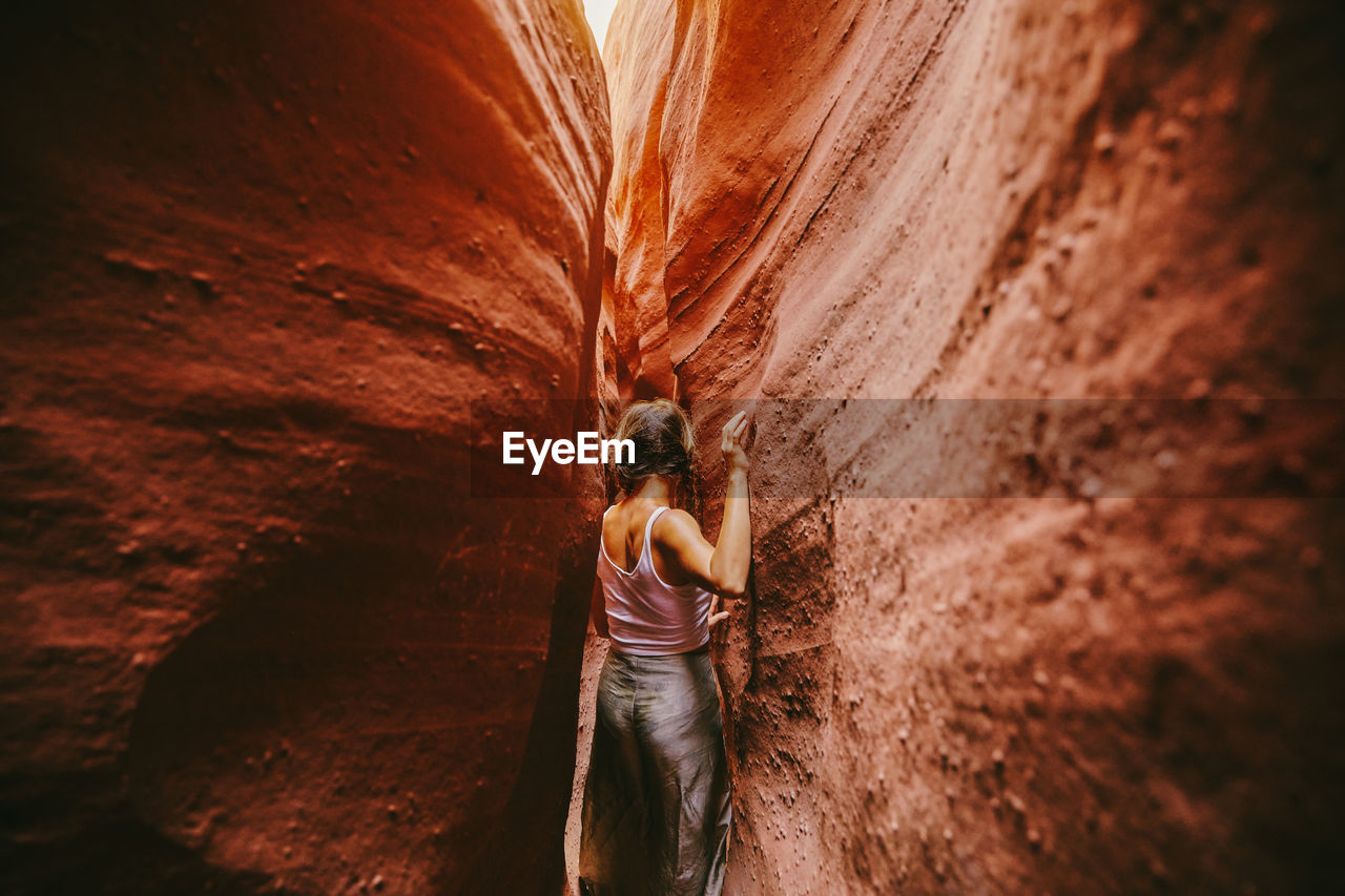 Young woman exploring narrow slot canyons in escalante, during summer