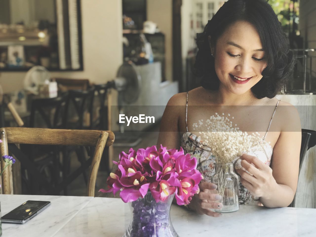 Smiling woman looking at flowers in cafe