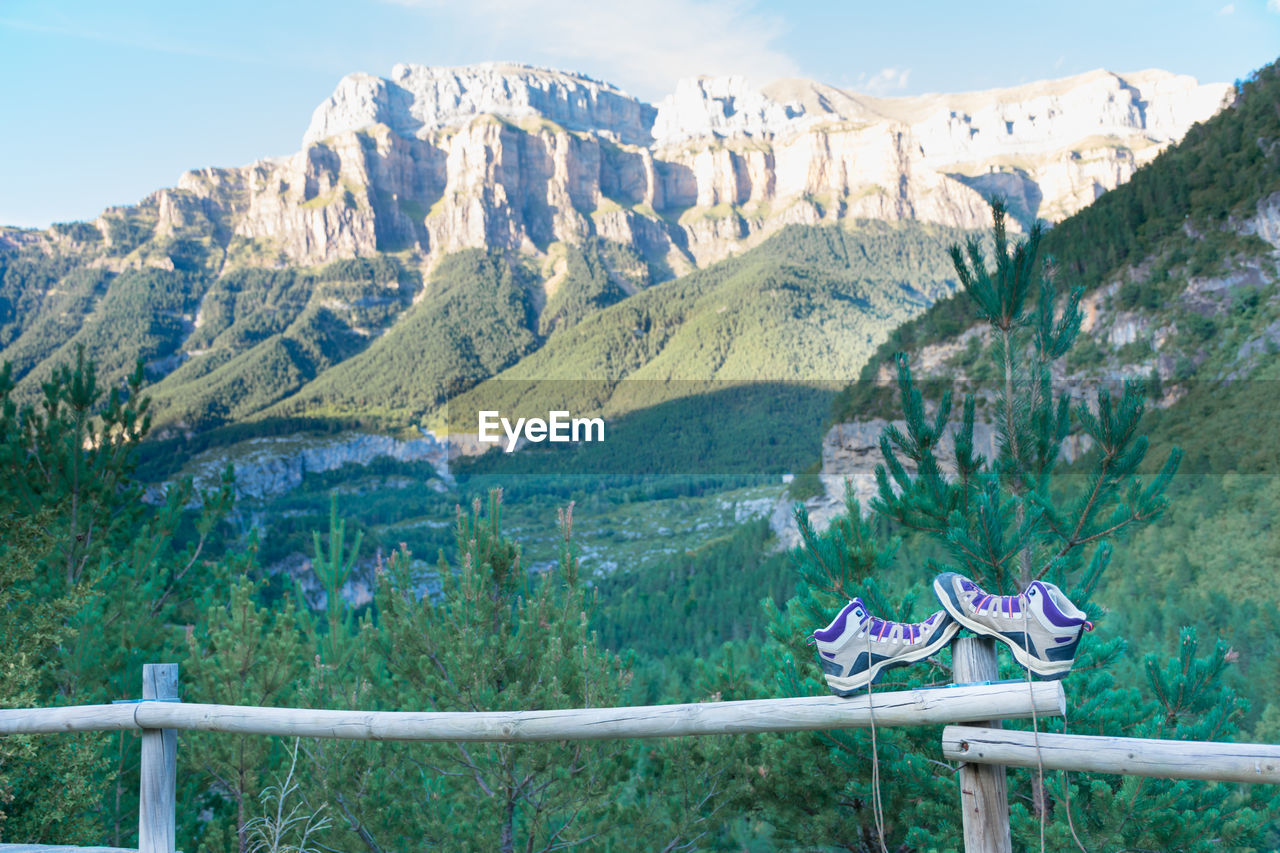 A pair of boots untied up and abandoned on a wooden railing and leaning on a post. the hiker has put out his boots to rest his feet after hiking for a time. horizontal photo with nobody.