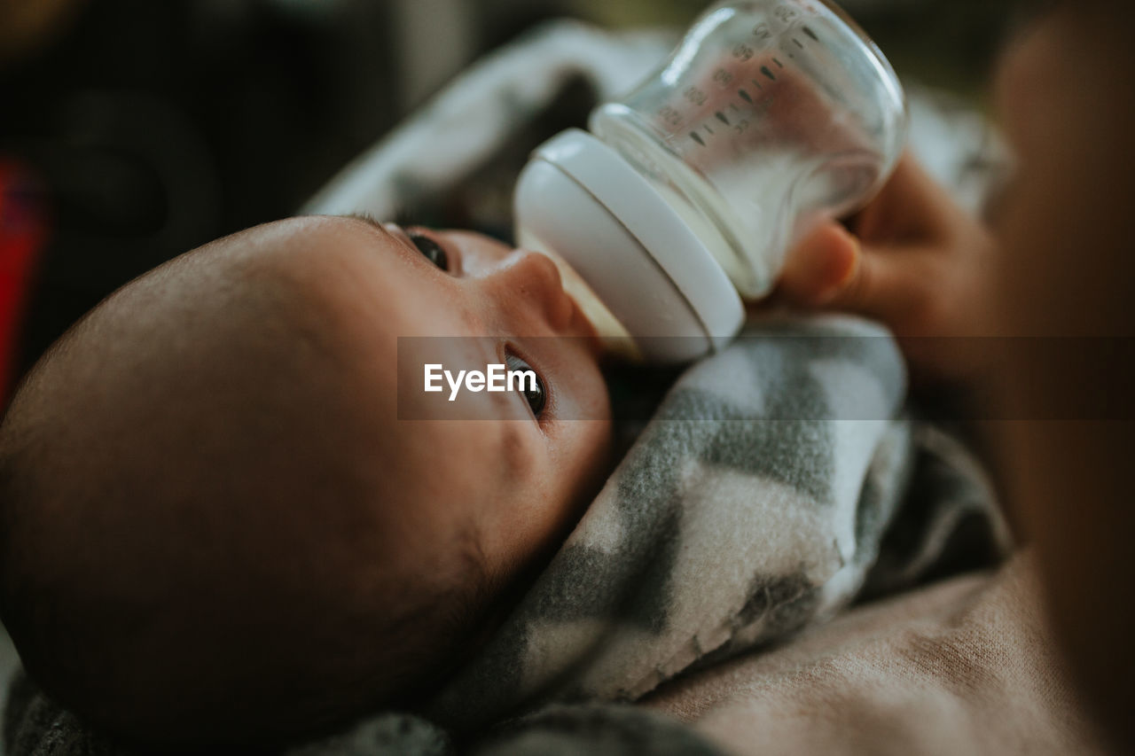 Close-up mother feeding baby milk with bottle